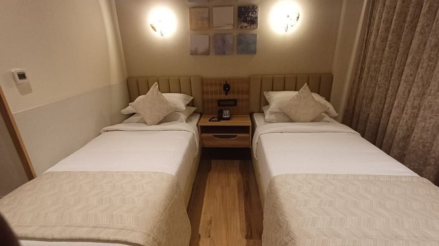 Image of a room with twin beds and a lights above the bed  at Hotel Raai, Hosur.