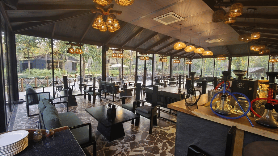 The spacious restaurant at Hotel Sonar Bangla Joypur Forest, Bankura features stone flooring and warm, amber lighting.