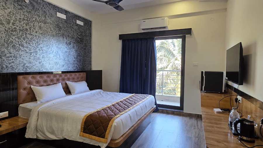 A bedroom with a king size bed, ceiling fan, and a glass door opening out to a balcony.