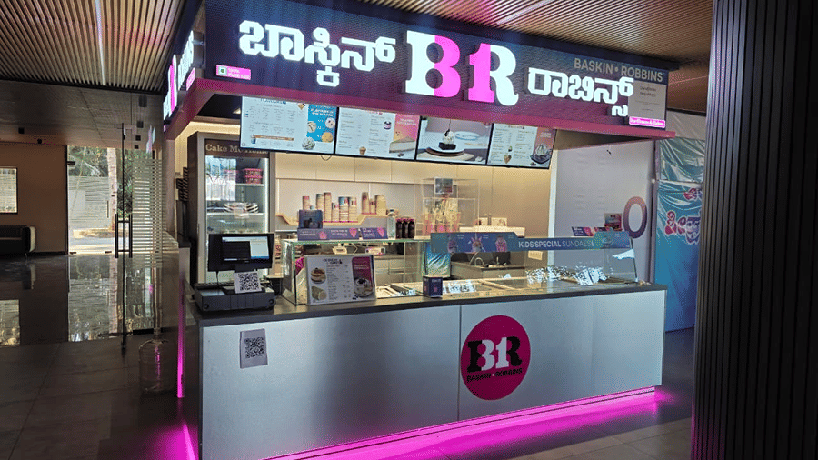 A dessert counter lit up with pink neon lighting, showing a menu board and glass display case.