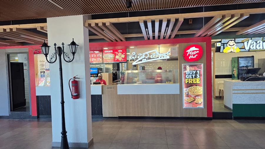 A hallway with a decorative lamp post, wooden pillar, and a food counter visible in the background.