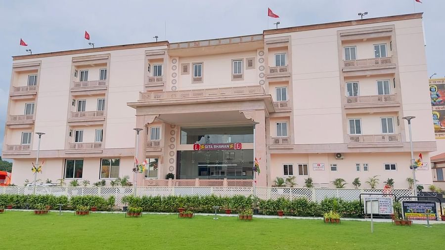 The front of a light-coloured building with a well-maintained green lawn - Kankidham Lords Inn