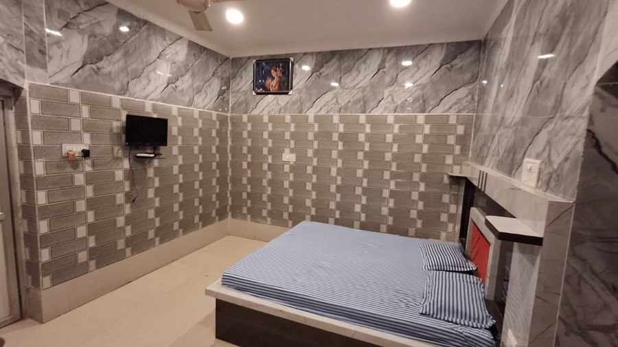 A Deluxe AC Room at Khairi Resorts is fully tiled on all 4 walls, with a TV placed opposite the bed.