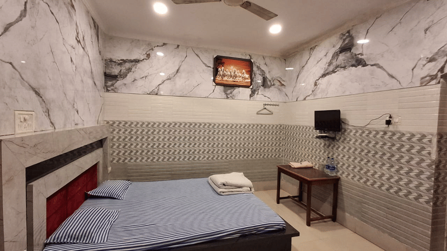 A television is hanging on a tiled wall opposite a double bed in a room at Khairi Resorts.