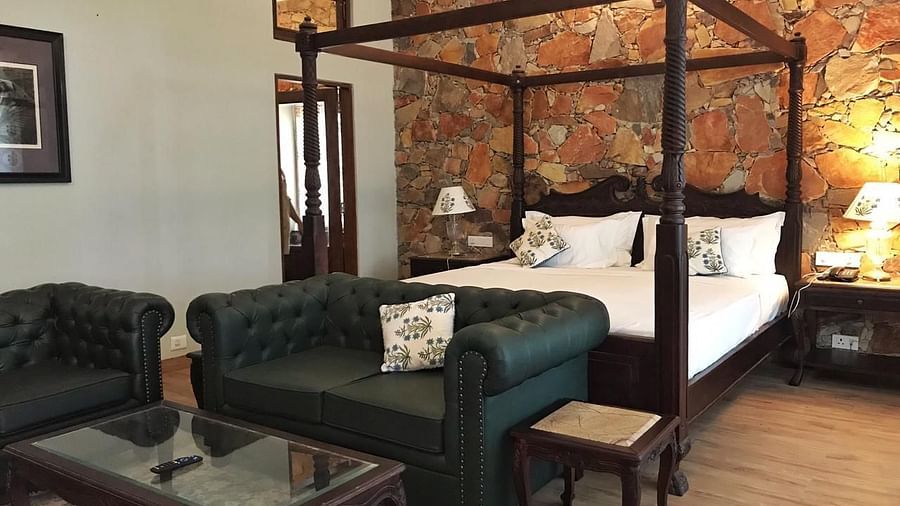 A well-appointed hotel bedroom featuring a four-poster bed and a green sofa - Khas Bagh, Jaipur.