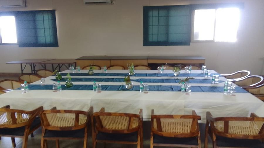 Large hall with rows of empty chairs with two small windows in the far end of the room - Lords Eco Inn Belagavi