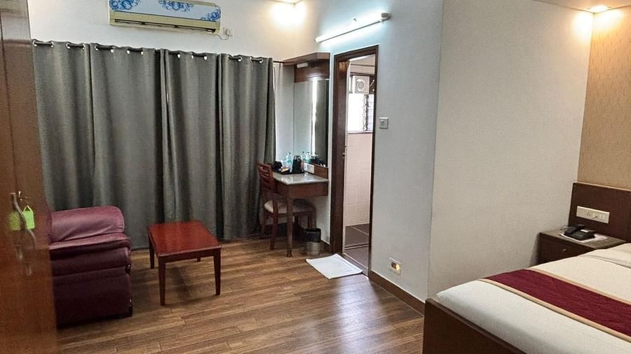 A comfortable bedroom with a large bed, wooden flooring, and a small sitting area offers a pleasant stay at Lords Midtown Suites.