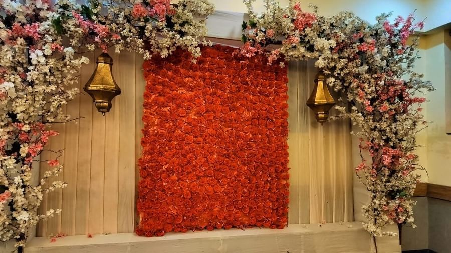 Decorative stage with red floral wall and flower arrangements at Max Hotel Prayagraj.