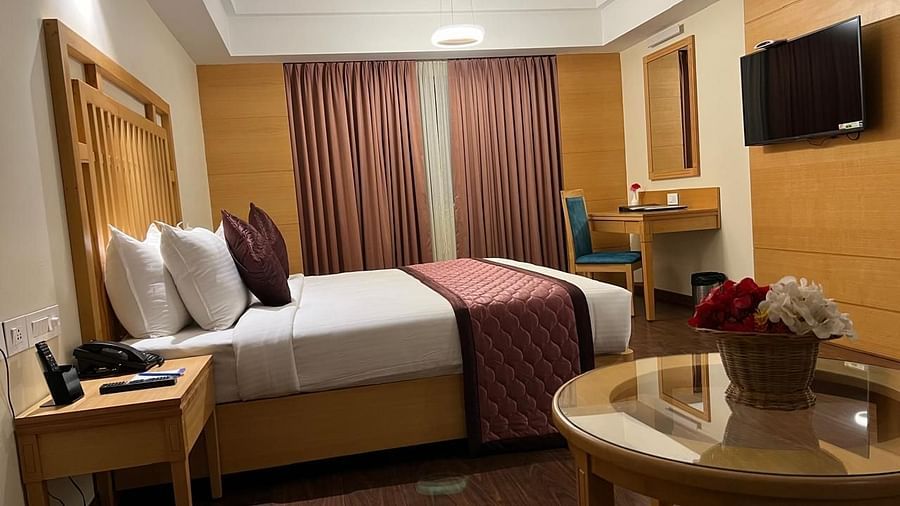 A modern, well-lit bedroom with a king-size bed, a flat-screen TV, and a desk- MM Legacy, Kanchipuram.