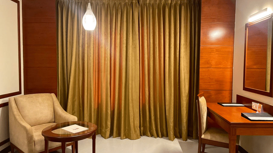 A seating area with a sofa, a table, chairs, a bulb, and a mirror. | MM Legacy, Kanchipuram