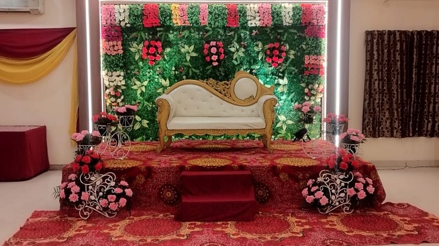 An event hall in Roorkee, elegantly arranged with a chair for the bride and groom adorned with flowers on the walls - Motel Divine International, Roorkee