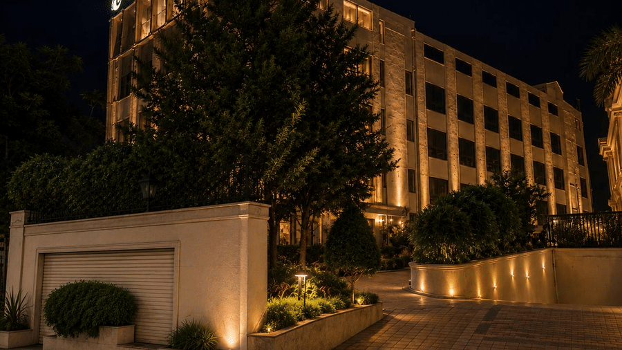 Exterior view of the illuminated main entrance driveway and building architecture at Ni Central Park at night.