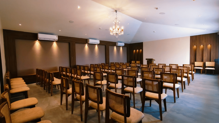 An event space filled with rows of wooden chairs facing a speaker podium at Savyasaachii Hotel.