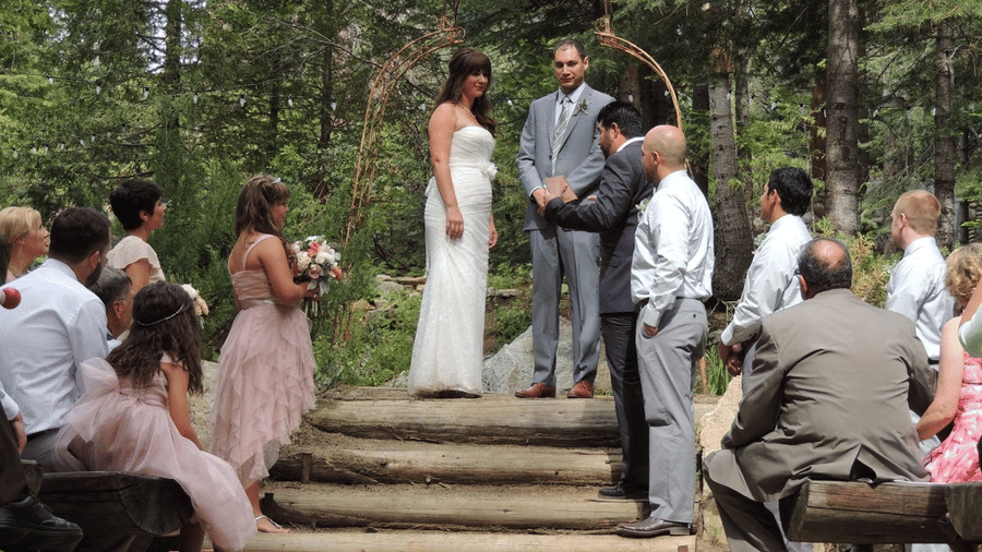 Outdoor woodland wedding ceremony with guests gathered as the couple exchanges vows at  Shaver Lake Village Hotel.