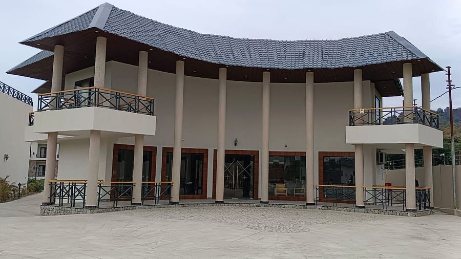 A modern resort building with a large porch and a grey tiled roof - Shervani Pebbles & Pines, Corbett.