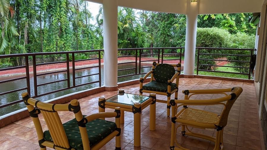 Outdoor seating area on a covered balcony with a scenic forest view at The Conservancy Bungalow.