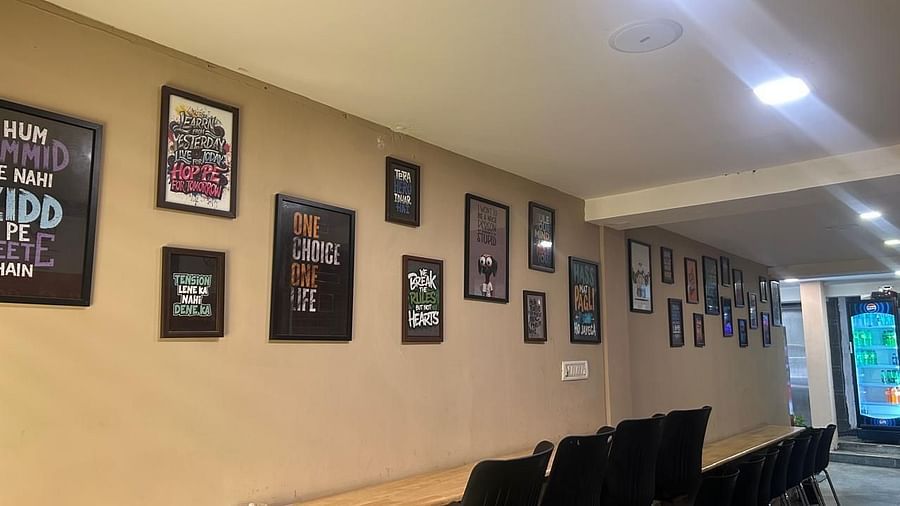 A hallway at The OnTime Hotel, Bangalore, with framed pictures on the wall and a long table with chairs.