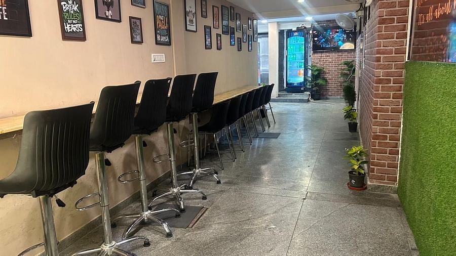 A longer view of the hallway at The OnTime Hotel, Bangalore, with office-style chairs and a plant.