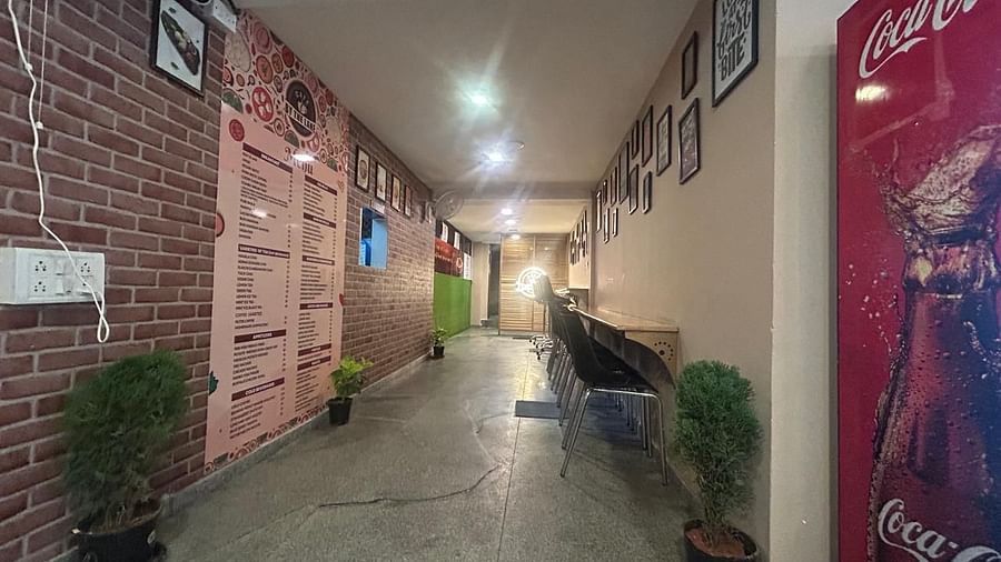 A view down a hallway at The OnTime Hotel, Bangalore, with exposed brick walls, a plant, and a red Coca-Cola vending machine.