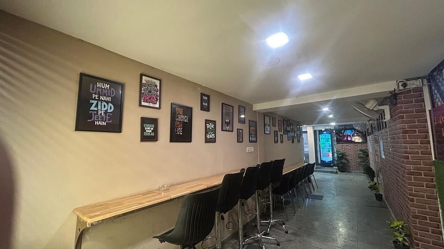 A hallway at The OnTime Hotel, Bangalore, with a long table, chairs, and framed pictures on the wall.