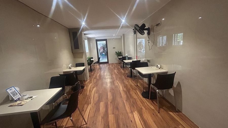 A long view of the dining area at The OnTime Hotel, Bangalore, with tables, chairs, and a hallway leading further into the hotel.