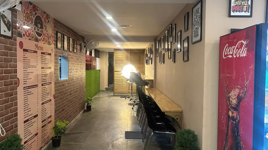 Another view down the hallway at The OnTime Hotel, Bangalore, showing a red Coca-Cola vending machine and framed pictures.