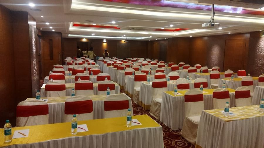 A conference hall set up with rows of tables and chairs, ready for attendees- The President Hotel Jayanagar, Bangalore