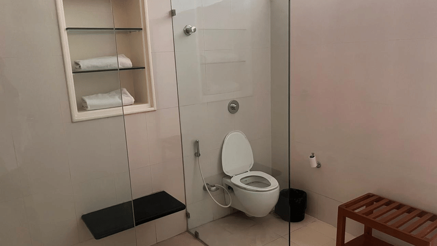 A view of the vanity area and walk-in shower separated by sleek glass panels, featuring minimalist tiling | Trance Sunderban Resort