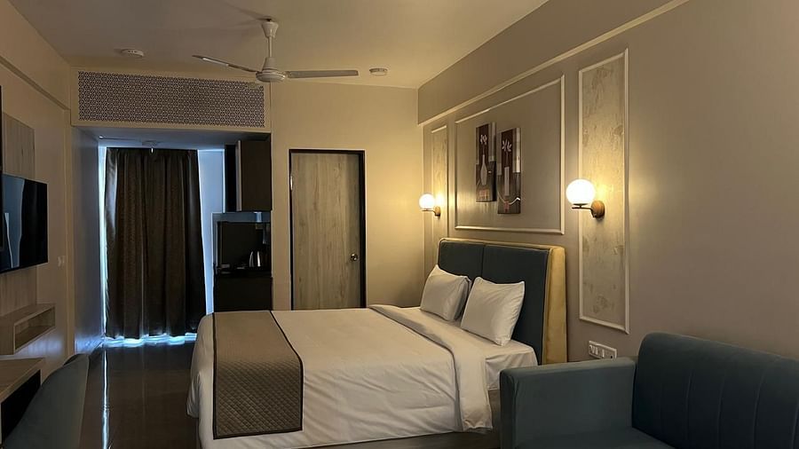 A side view of the room featuring a large bed, warm lighting, and a pathway with sheer curtains at Urban Suites by BluSalzz, Jaipur.