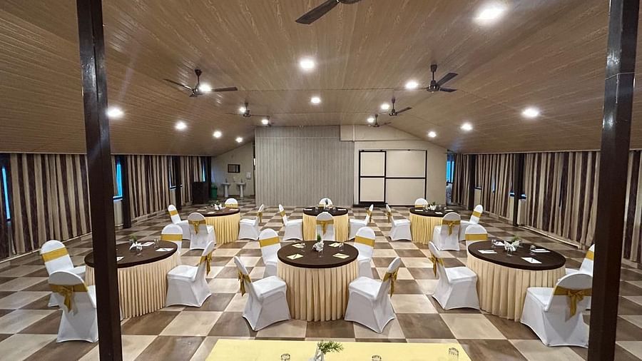 An indoor event space is shown from a different angle, highlighting the table settings | Ballroom | Woodstock Resorts, Coorg