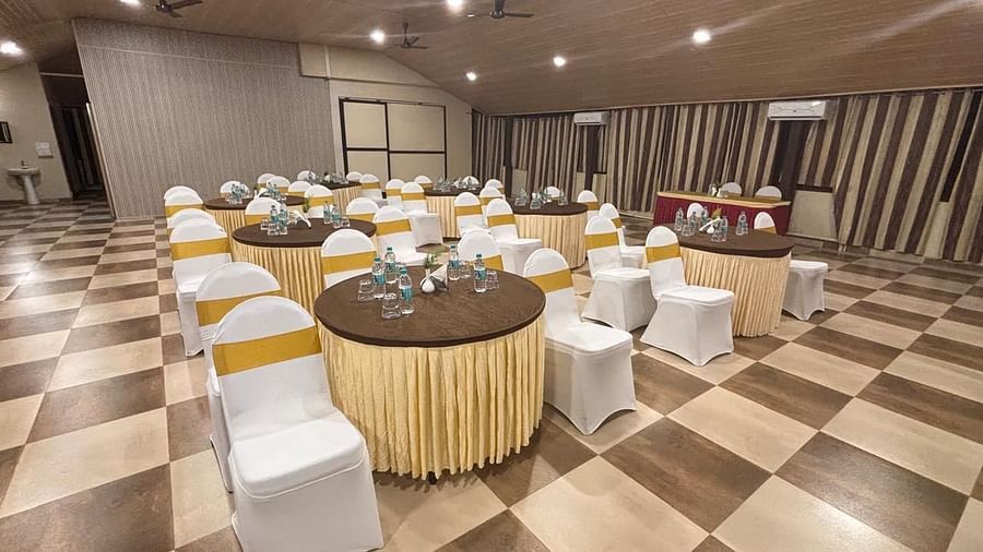 A banquet hall setup with round tables and chairs neatly arranged under ambient lighting | Ballroom | Woodstock Resorts, Coorg | Woodstock Resorts, Coorg
