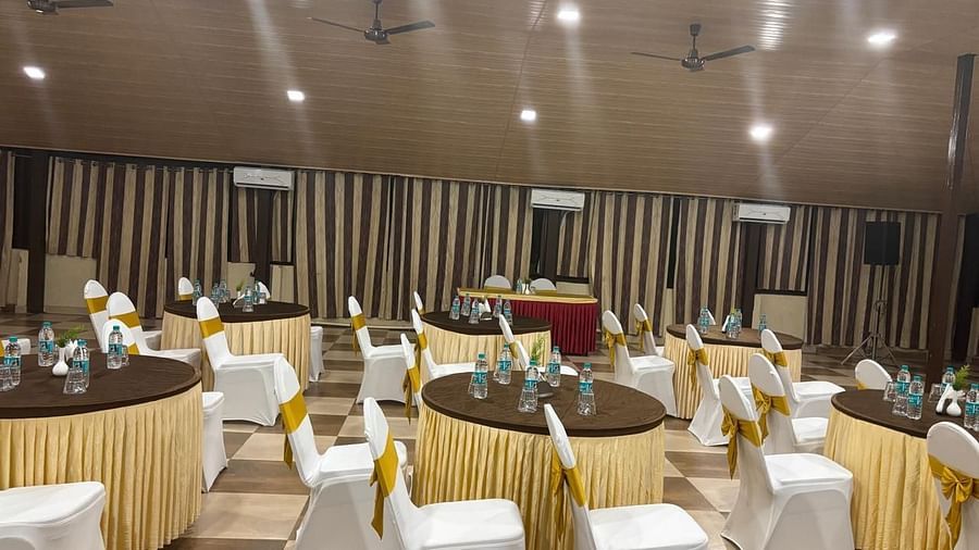 A table setting with floral centrepieces and chairs in a banquet hall | Ballroom | Woodstock Resorts, Coorg
