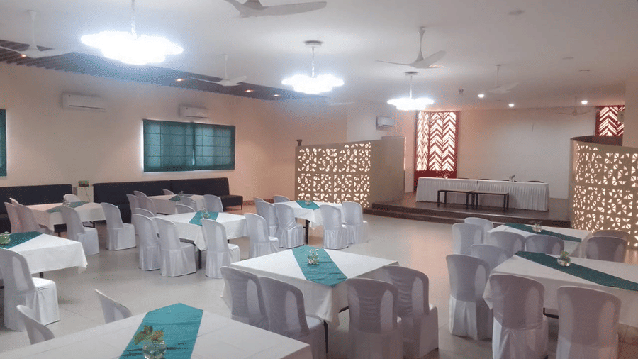 An event room with tables and chairs, a ceiling fan, and patterned curtains - Lords Eco Inn Belagavi