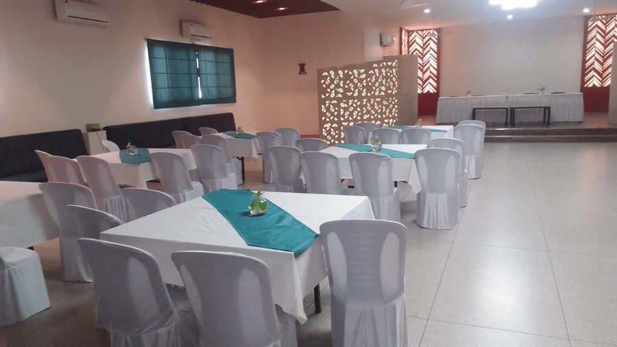 A banquet hall with tables draped with a white table cloth and turquoise runners - Lords Eco Inn Belagavi