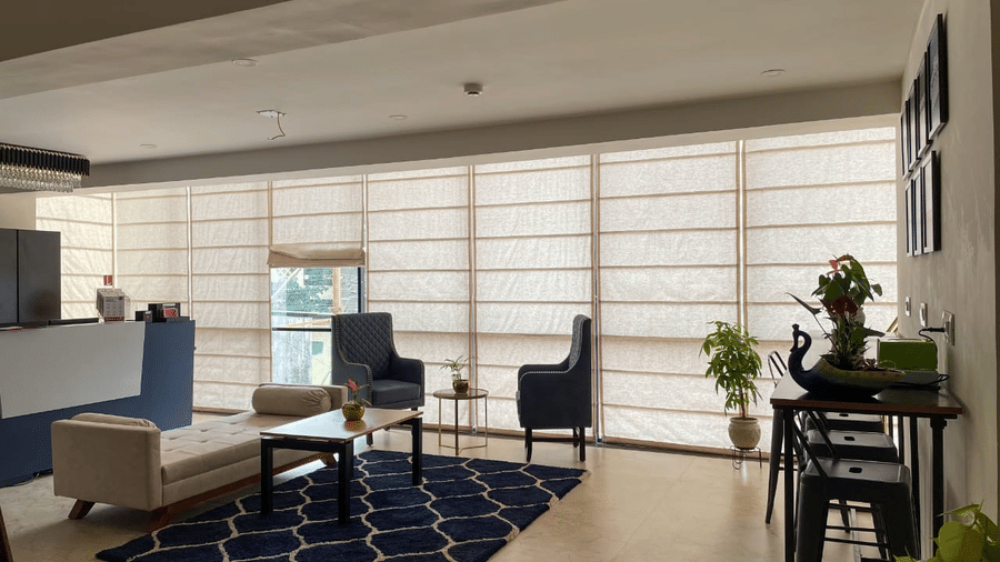 Hotel lobby with modern seating area, patterned rug, and large window blinds - Lords Eco Inn Belagavi