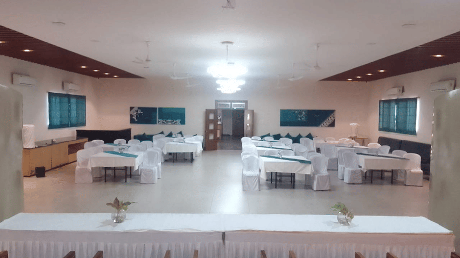 A spacious event space with multiple tables and chairs arranged - Lords Eco Inn Belagavi