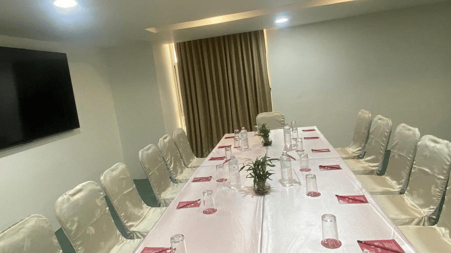 A banquet hall with a TV and ceiling lights and windows with curtains