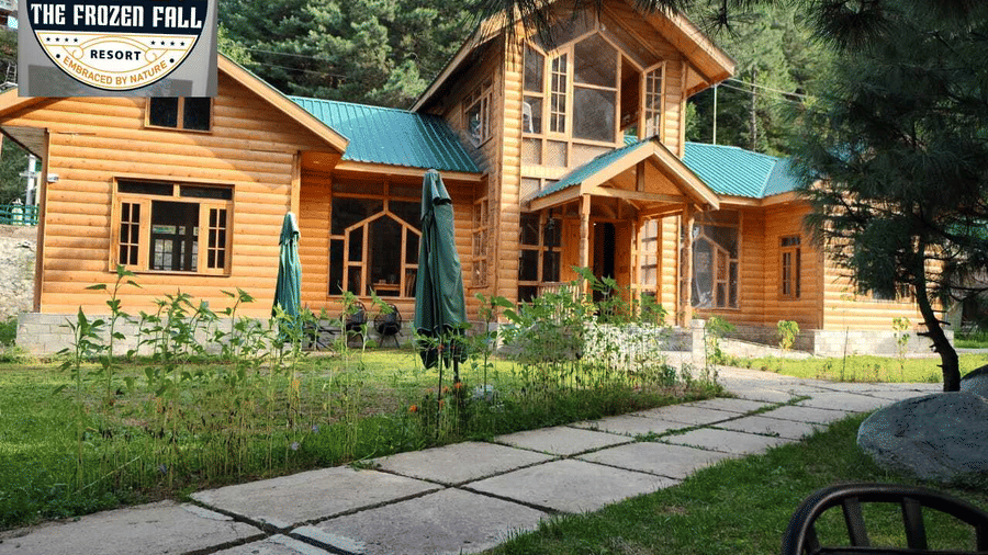 A multi-storey wooden villa building at Dawat e Drung by FrozenFall Resort, Drung, Tangmarg, featuring paved walkways and a green garden lawn.