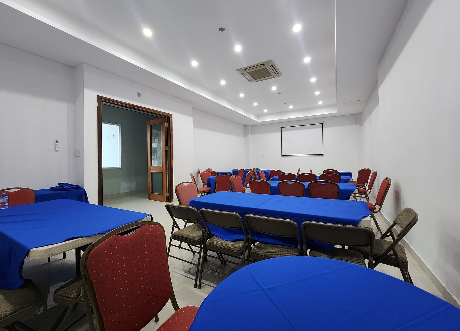 An image of Imagination  Lounge, our event hall in Montego Bay with chairs placed around long tables and a projector - Hotel 39, Jamaica (Montego Bay)
