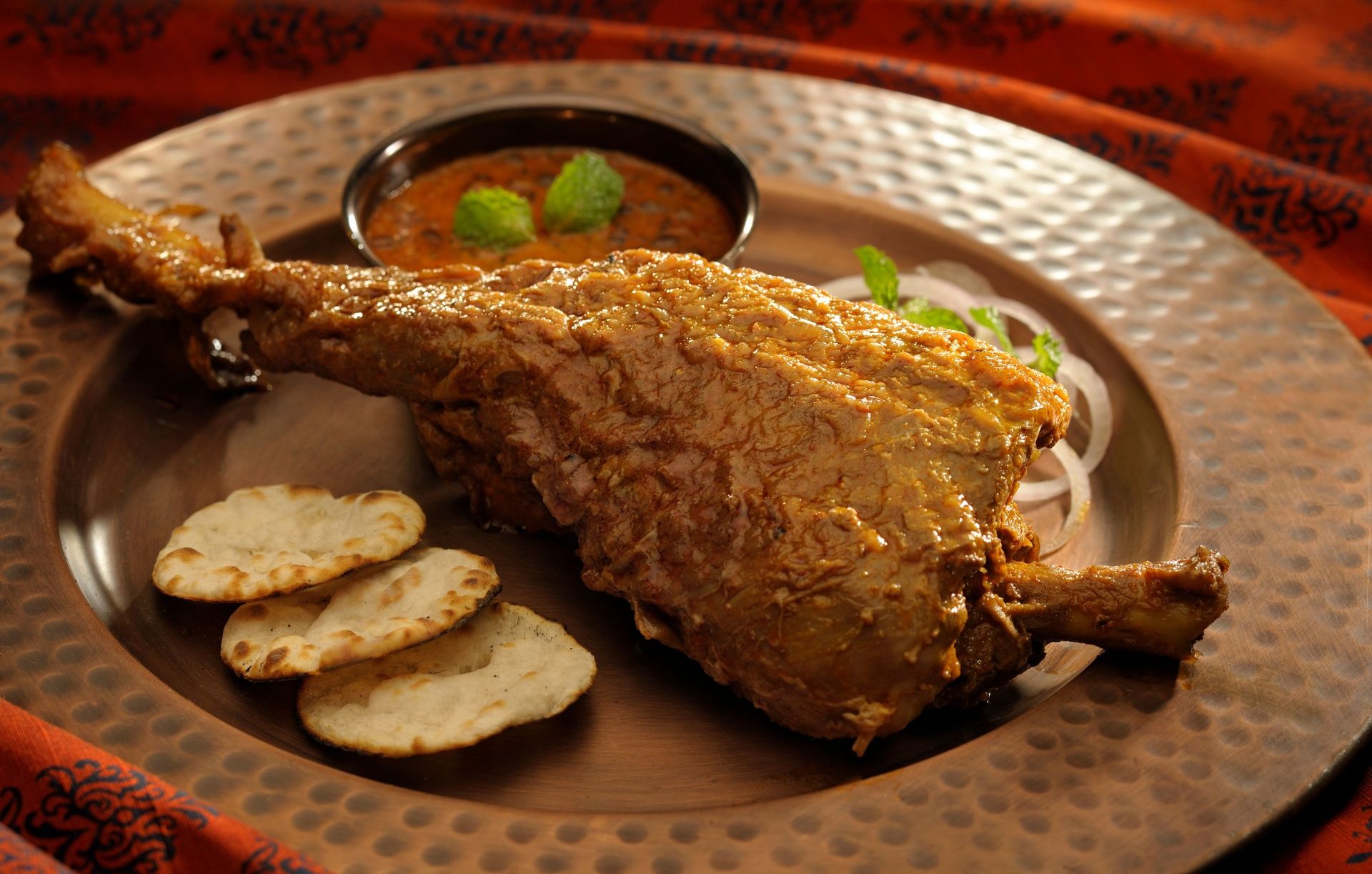 Roasted lamb leg (Raan) with gravy and naan.