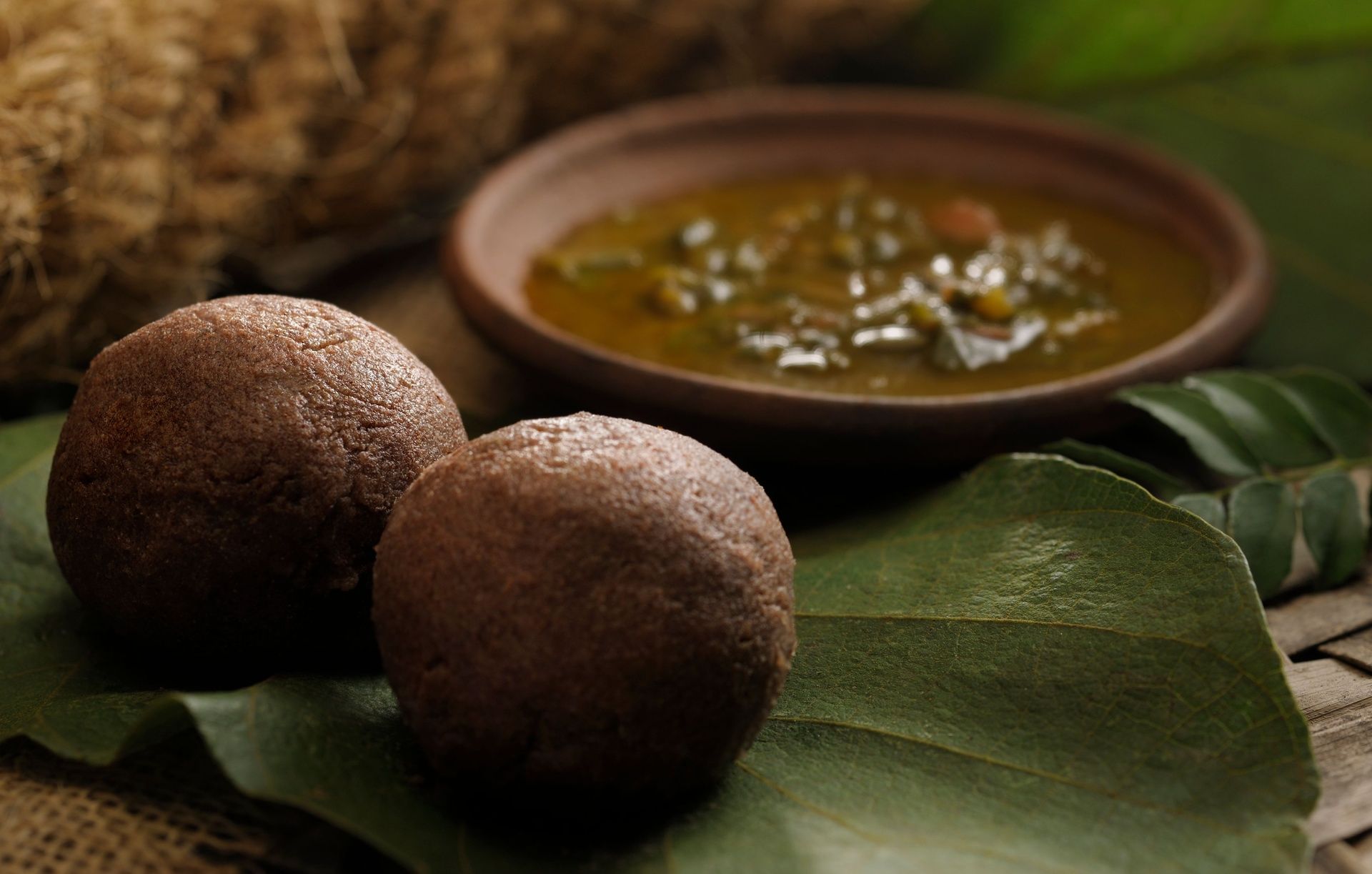 Two Ragi Mudde balls with a bowl of curry.