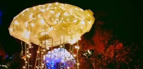 An illuminated jellyfish-shaped light decoration against a dark background.