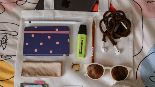 A tote bag with various travel essentials placed on it.