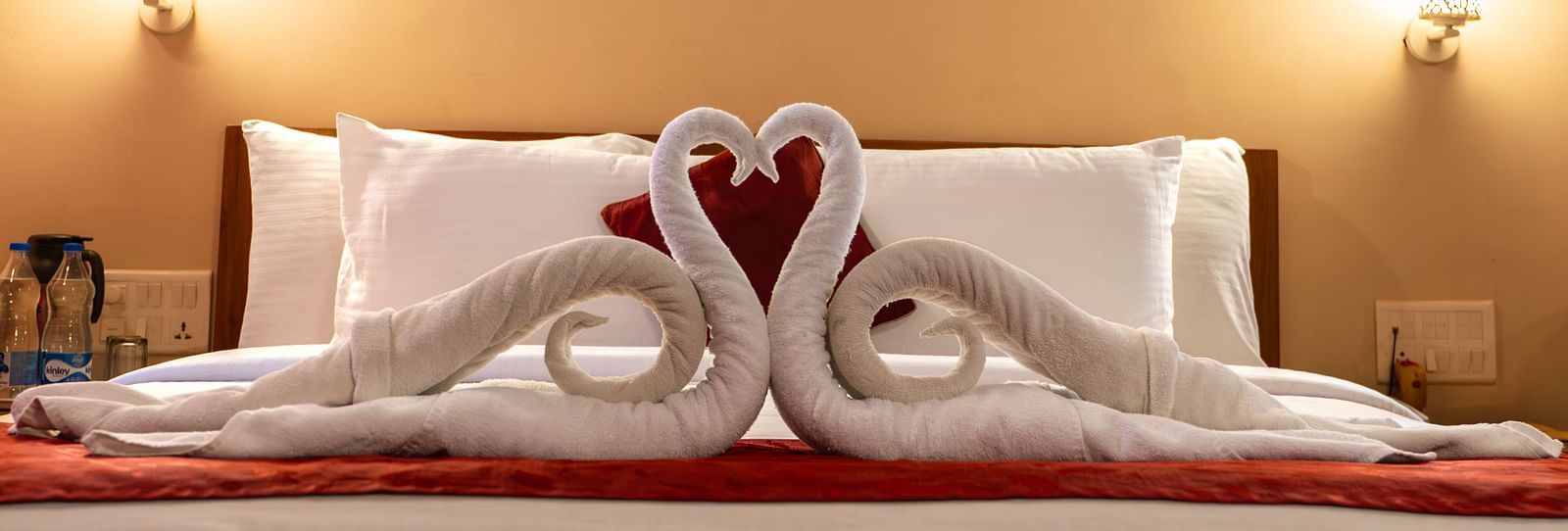 A close-up of bed of Attic Villa displays decorative towel swans | Woodstock Resorts, Coorg