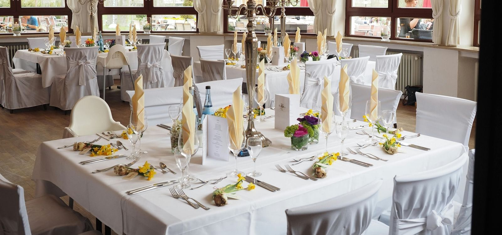 A restaurant depicting seating arrangement with cutlery and decorative items on the table