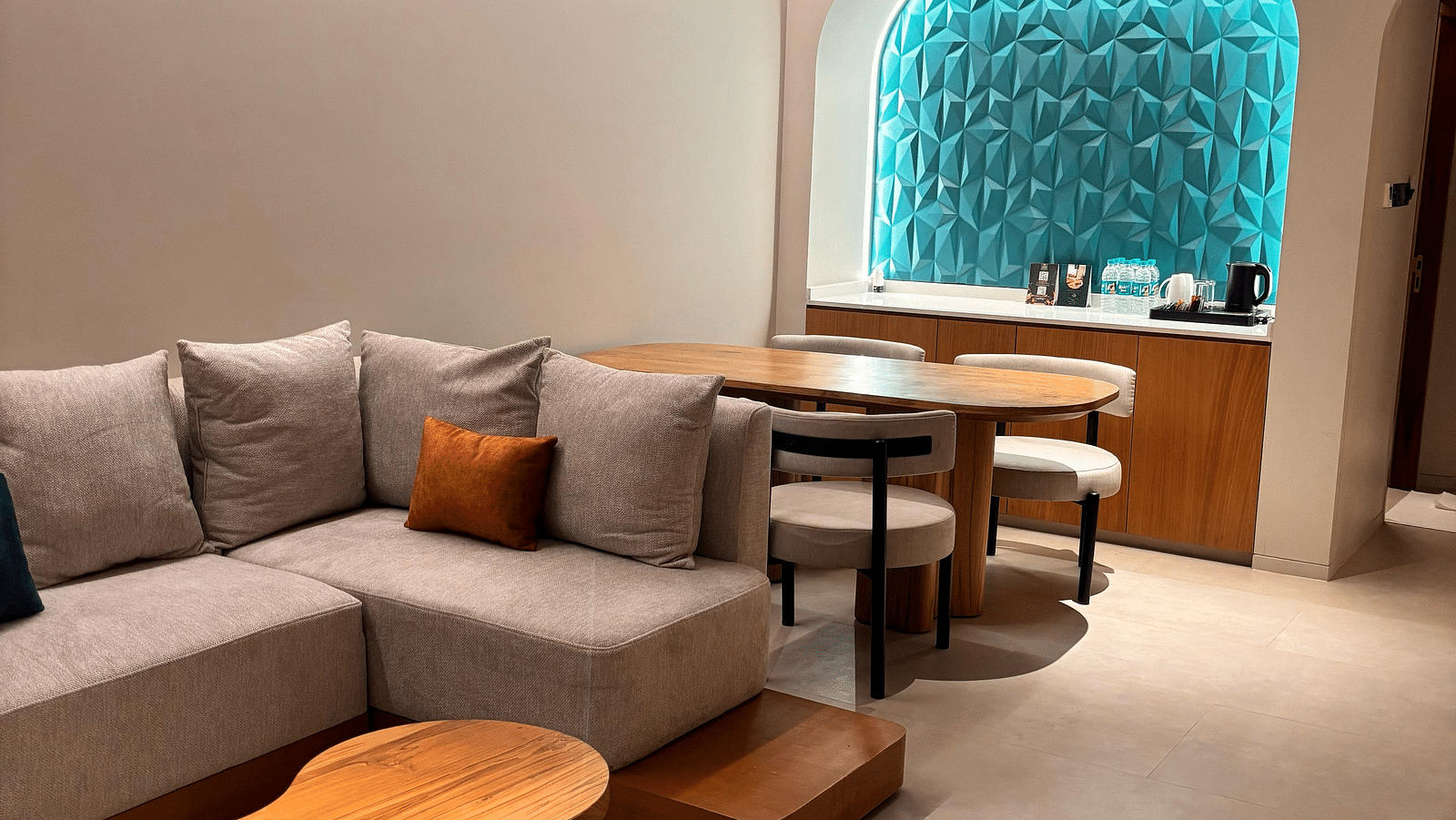 A living area at Swosti Premium Beach Resorts, Puri, with a couch, chairs, and an arched doorway.