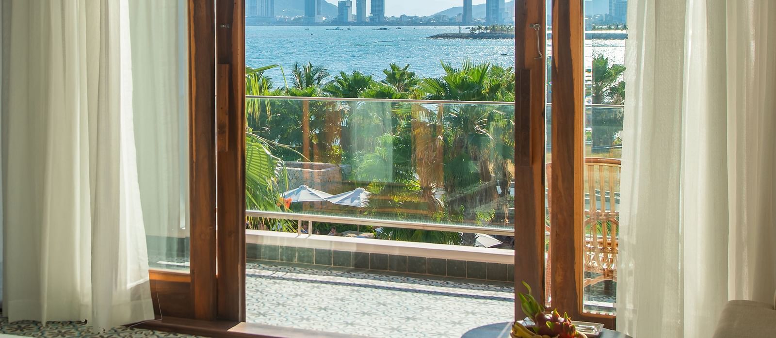 Step onto the balcony through glass doors framed in elegant wood, opening up to a breathtaking view that captivates the senses - Alibu Resort Nha Trang