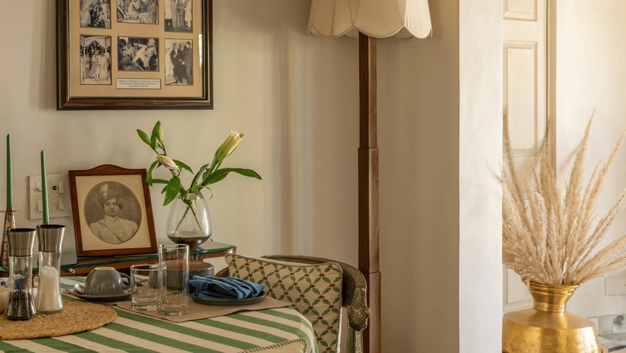 Bedroom with green bedding, a bedside lamp, wall art, and a white arched doorway at Barwara Kothi, Jaipur.