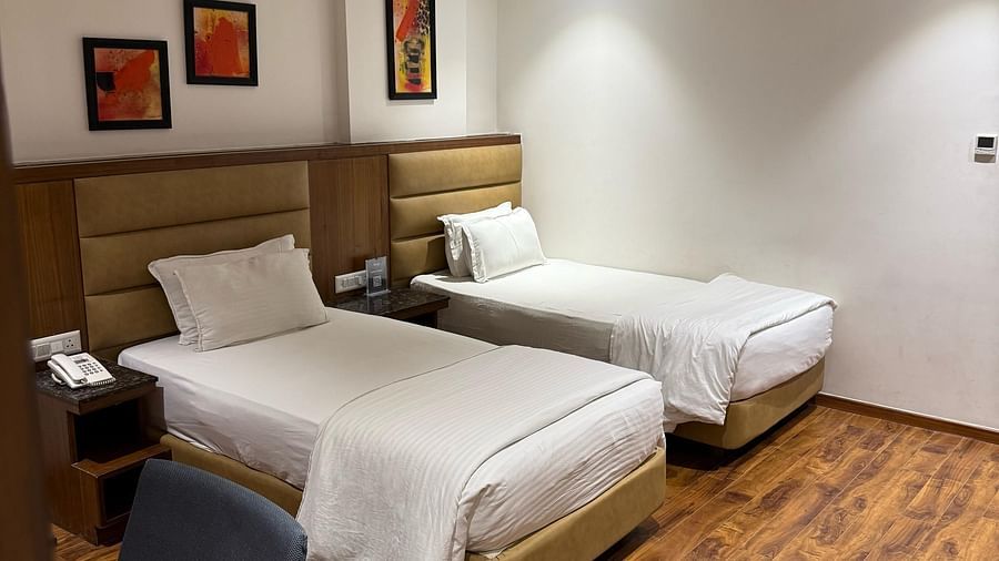 A bedroom at Kyriad Hotel, Gulbarga, with two made beds and artwork on the wall.