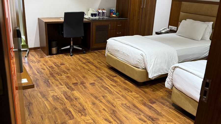 A bedroom at Kyriad Hotel, Gulbarga, with two made beds, a desk, and a chair.